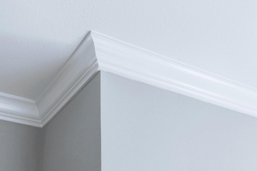 White crown molding mitered at an outside corner against a light gray wall and white ceiling