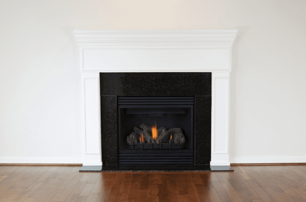 White wood mantel with crown molding and black granite surround around a gas fireplace on hardwood floors